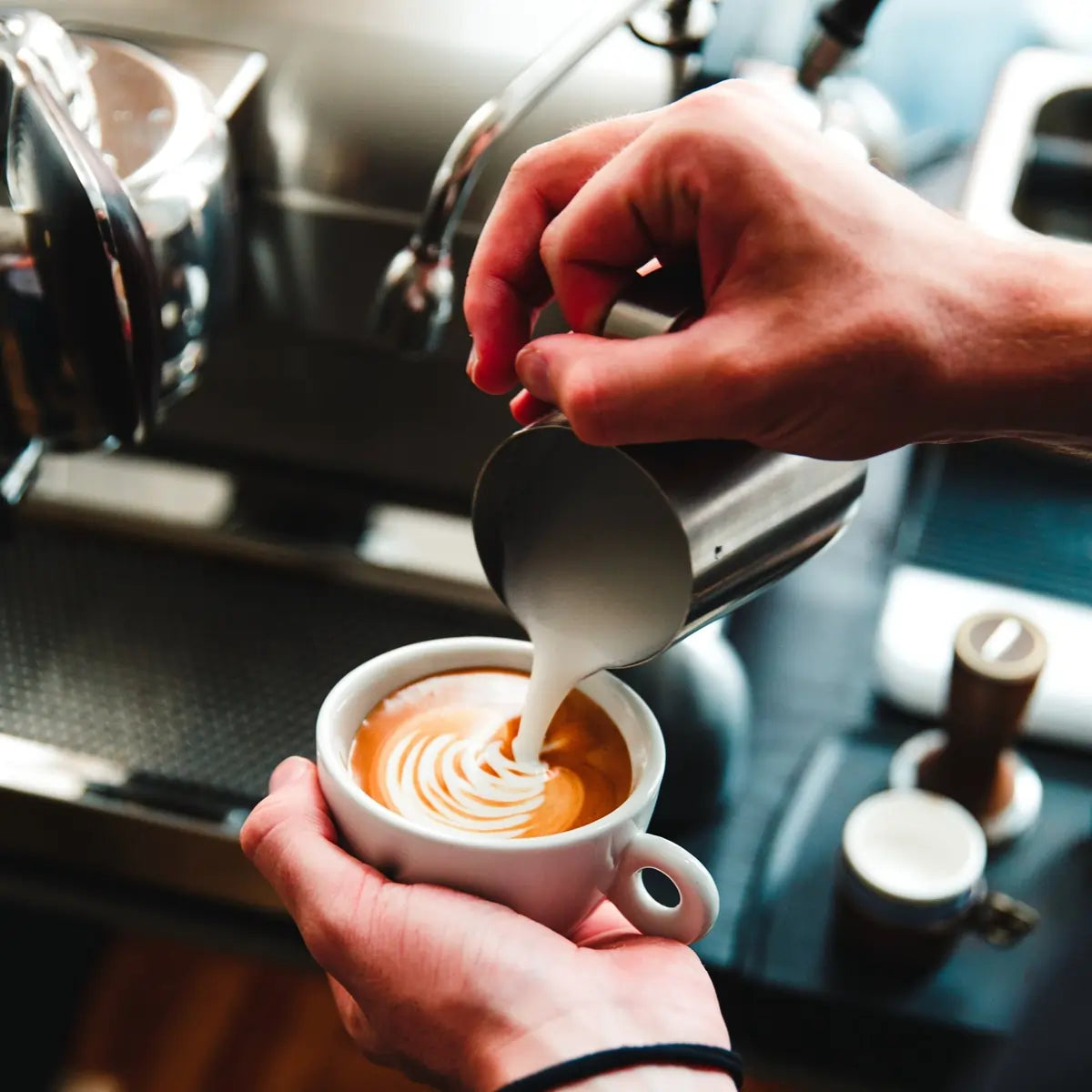 Barista wlewa spienione mleko do espresso – przygotowanie latte art w kawiarni - JAVA Coffee B2B