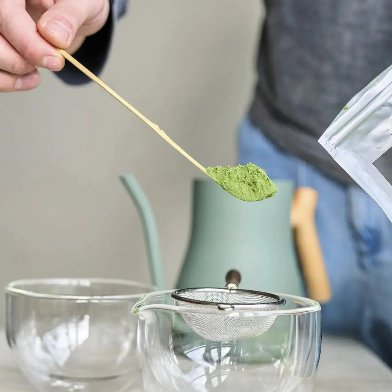Chashaku – tradycyjna bambusowa łyżeczka do matchy w użyciu, z porcją sproszkowanej herbaty matcha nad sitkiem