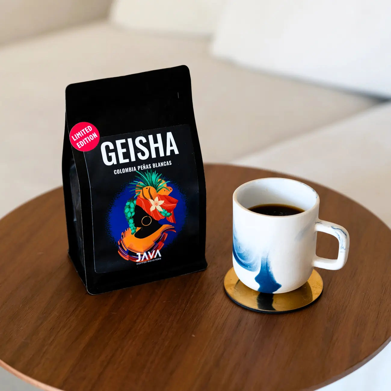 Kawa specialty Colombia Geisha Peñas Blancas Limited Edition – Java Coffee Roasters, paczka kawy i filiżanka na stoliku
