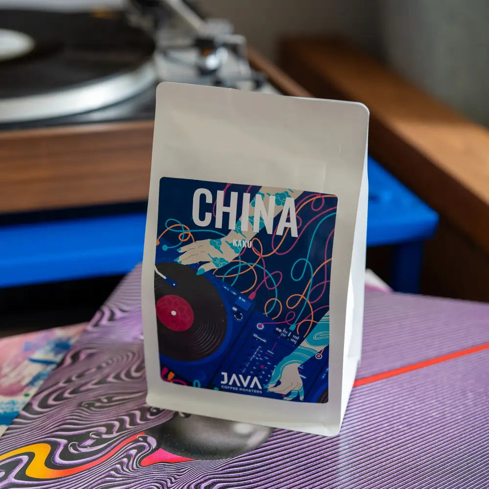 Kawa China Kaku JAVA Coffee Roasters – opakowanie kawy speciality z Chin na tle winyli i gramofonu, idealna do espresso w gastronomii