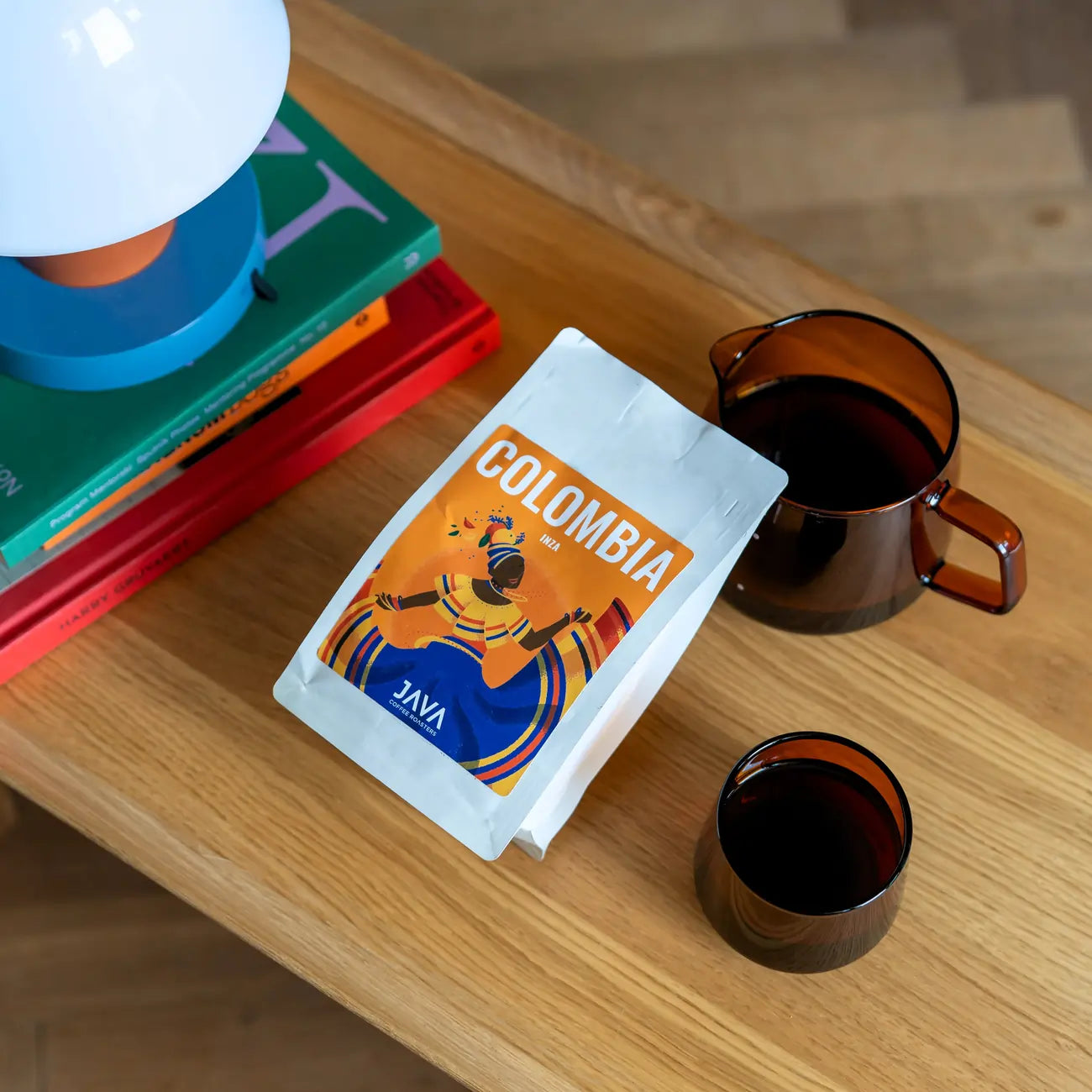 Kawa Java Coffee Colombia Inza – paczka kawy specialty na drewnianym stole obok dzbanka i filiżanki z kawą
