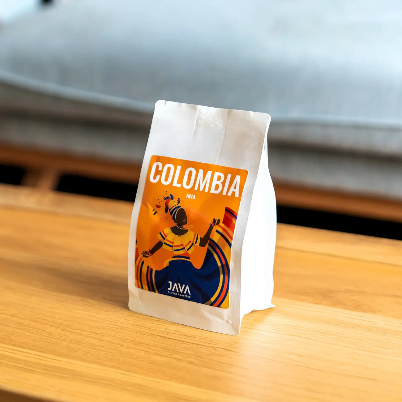 Kawa Java Coffee Colombia Inza – paczka specialty z kolorową etykietą inspirowaną kulturą Kolumbii, ustawiona na drewnianym stole