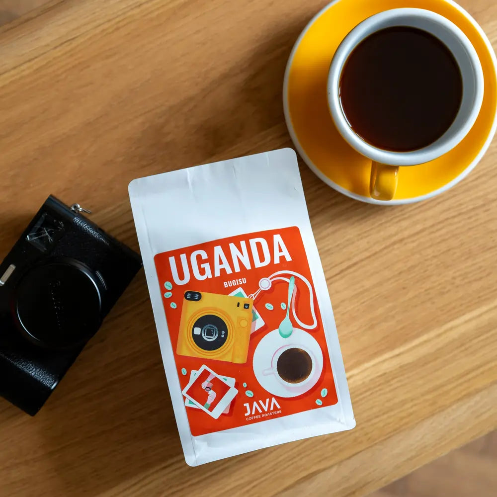 Kawa Uganda Bugisu JAVA Coffee Roasters – opakowanie kawy ziarnistej arabica z Ugandy, filiżanka czarnej kawy i aparat na stole, idealna do gastronomii i biur
