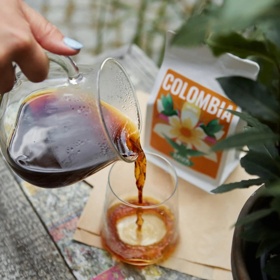 Parzenie kawy Colombia Tolima JAVA Coffee – nalewanie naparu z przelewu do szklanki, w tle opakowanie kawy specialty z Kolumbii
