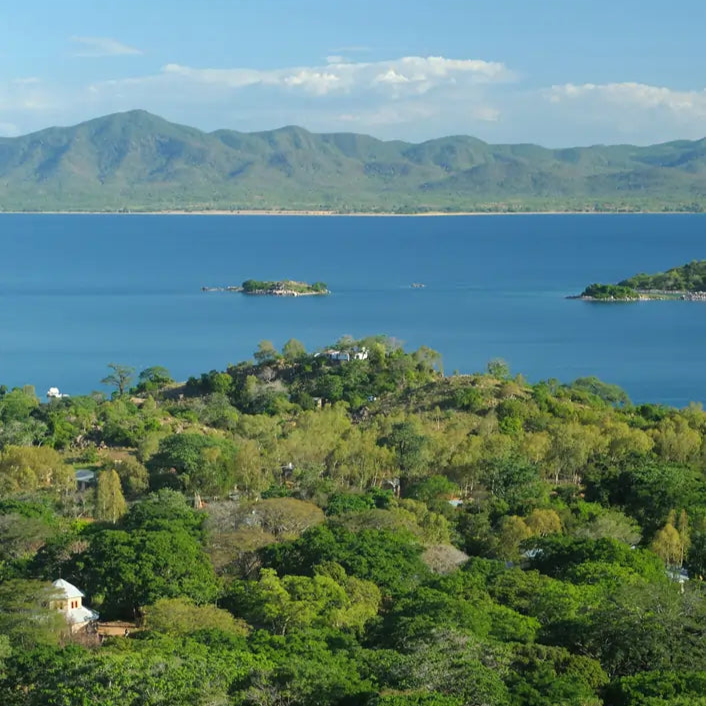 Panorama Mangochi w Malawi – zalesione wzgórza, zabudowania i Jezioro Malawi z pasmem górskim w tle. Widok z lotu ptaka.