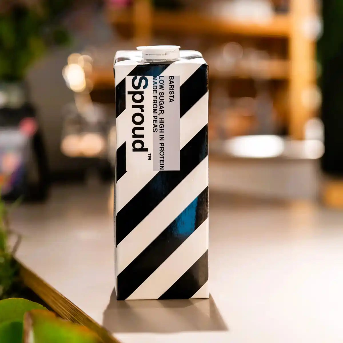 Karton napoju roślinnego Sproud Barista 1L ustawiony na stole – wegański napój z grochu stworzony do kaw mlecznych, bogaty w białko i o niskiej zawartości cukru.