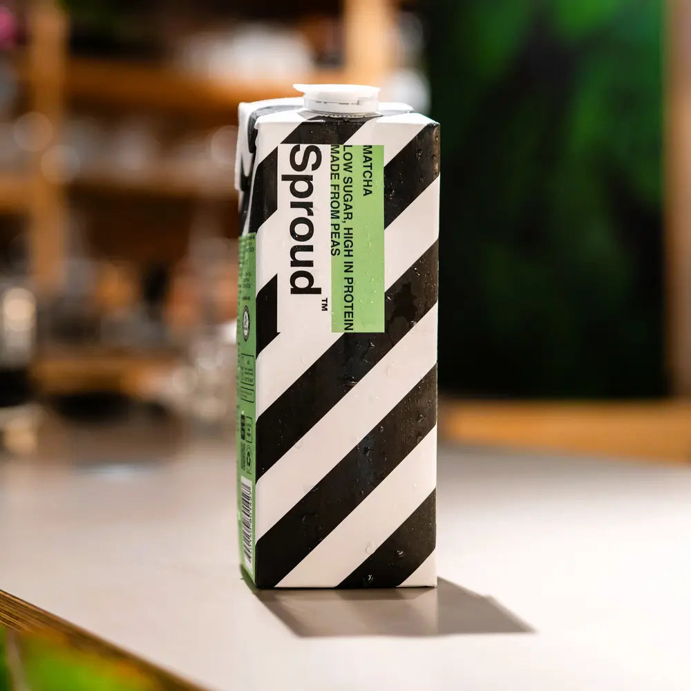 Karton napoju roślinnego Sproud Matcha 1L na stole – wegański napój z grochu o smaku matcha, wysokobiałkowy i niskocukrowy.