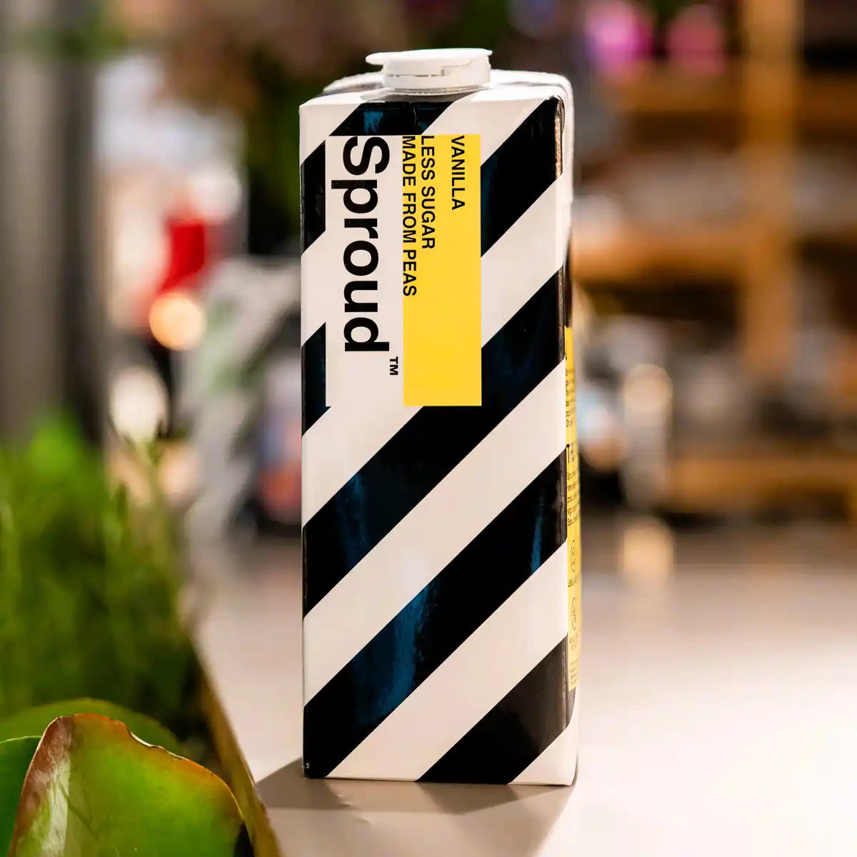 Karton napoju roślinnego Sproud Vanilla 1L ustawiony na stole – wegański napój z grochu o smaku waniliowym, źródło białka, z obniżoną zawartością cukru.