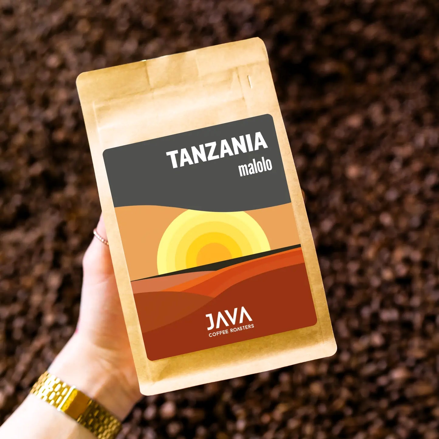 Kawa Tanzania Malolo od JAVA Coffee Roasters trzymana w dłoni na tle ziaren kawy