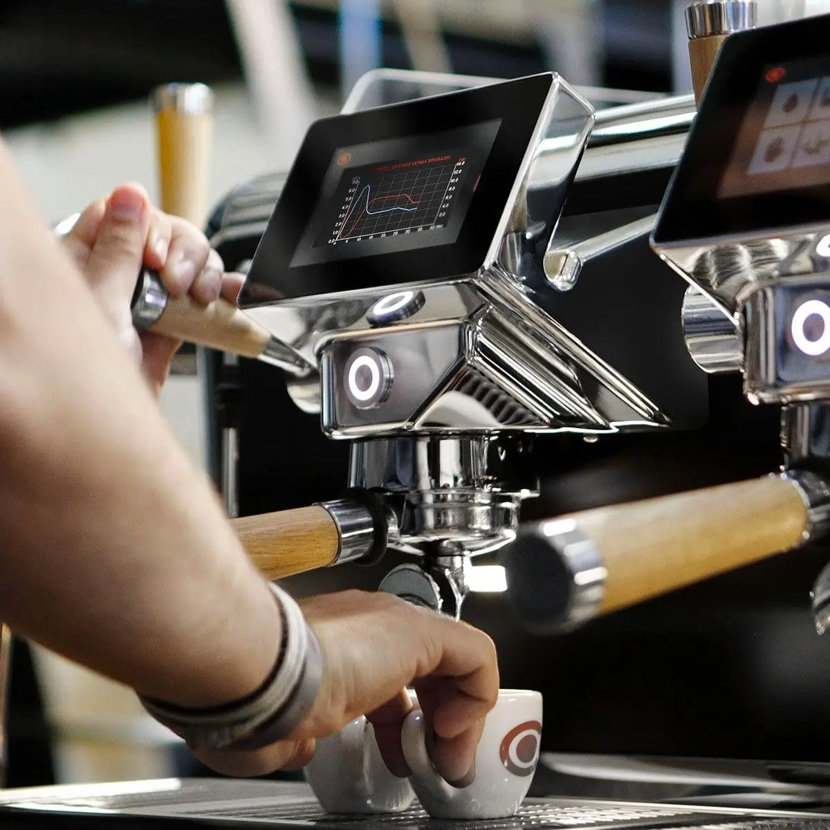 Astoria Storm – barista podczas ekstrakcji espresso, ekran kontrolny i kolba z drewnianą rączką, profesjonalny ekspres Astoria Storm w kawiarni