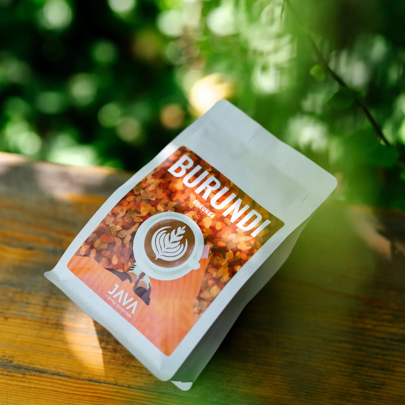 Opakowanie kawy specialty Burundi Burunga od JAVA Coffee Roasters na drewnianym stole w naturalnym świetle.