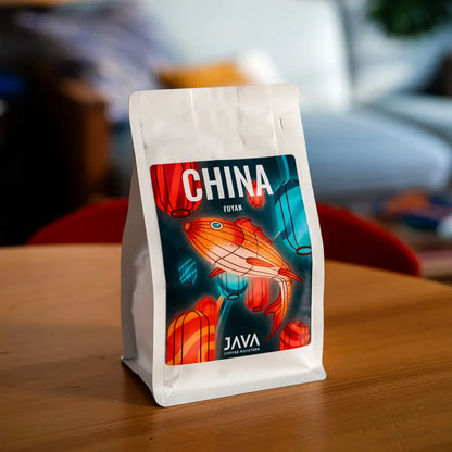 Opakowanie kawy specialty China Fuyan od JAVA Coffee Roasters ustawione na drewnianym stole – zdjęcie lifestyle z wyeksponowaną etykietą produktu
