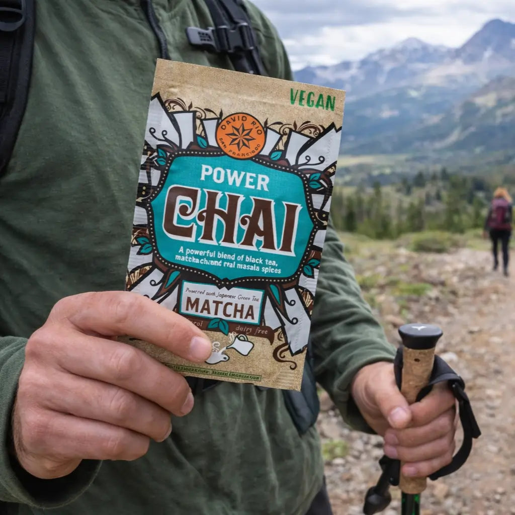 Power Chai Matcha David Rio – wegańska saszetka chai z matchą trzymana w dłoni podczas górskiej wędrówki, wygodna porcja na wynos