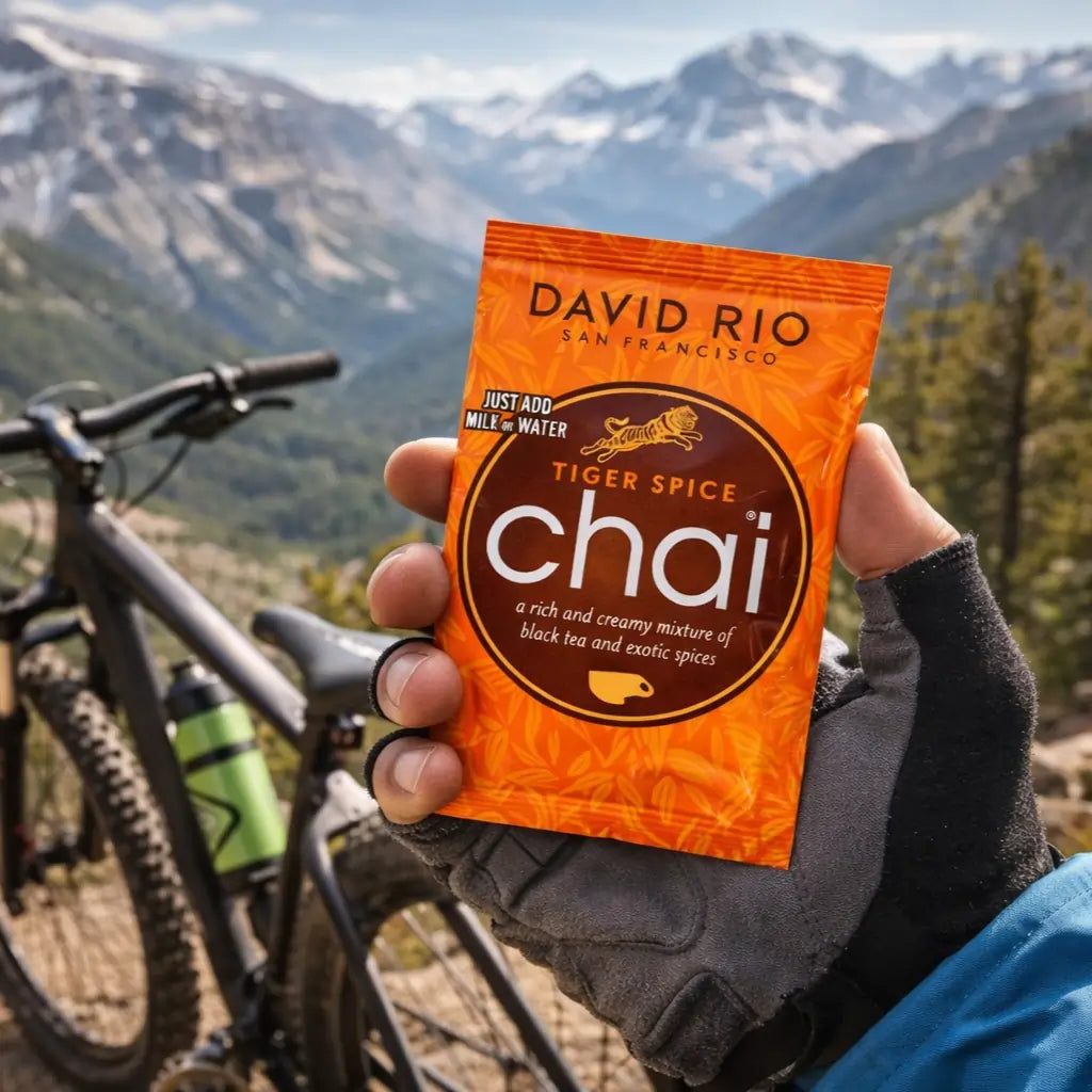 Chai Tiger Spice David Rio – pojedyncza saszetka chai latte trzymana w dłoni w górach, idealna porcja napoju na wyprawę i outdoor