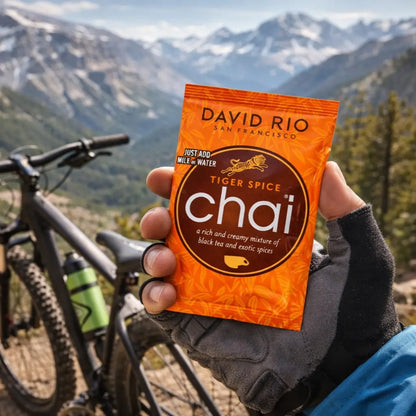Chai Tiger Spice David Rio – pojedyncza saszetka chai latte trzymana w dłoni w górach, idealna porcja napoju na wyprawę i outdoor