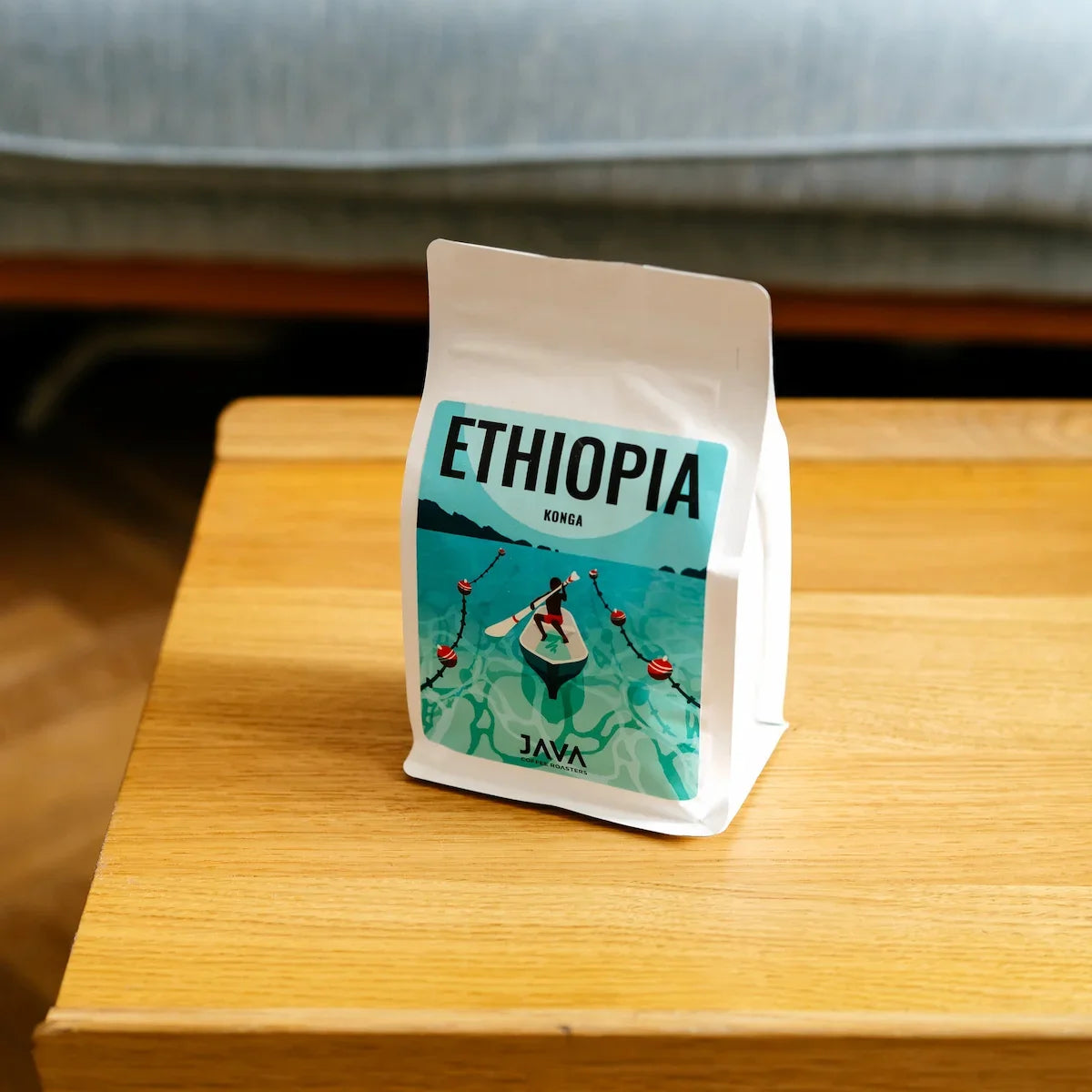 Opakowanie kawy specialty Ethiopia Konga od JAVA Coffee Roasters ustawione na drewnianym stole.
