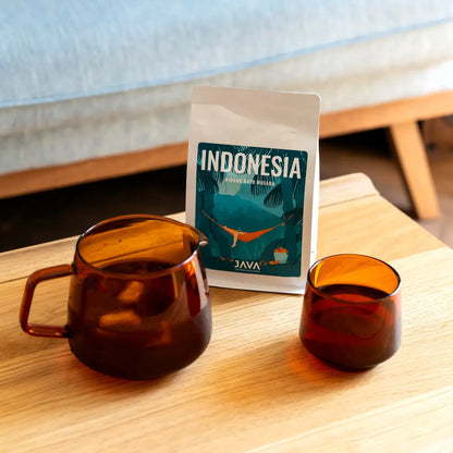 Kawa specialty Indonesia Ribang Gayo Musara od JAVA Coffee Roasters z zaparzoną kawą w bursztynowych naczyniach na drewnianym stoliku