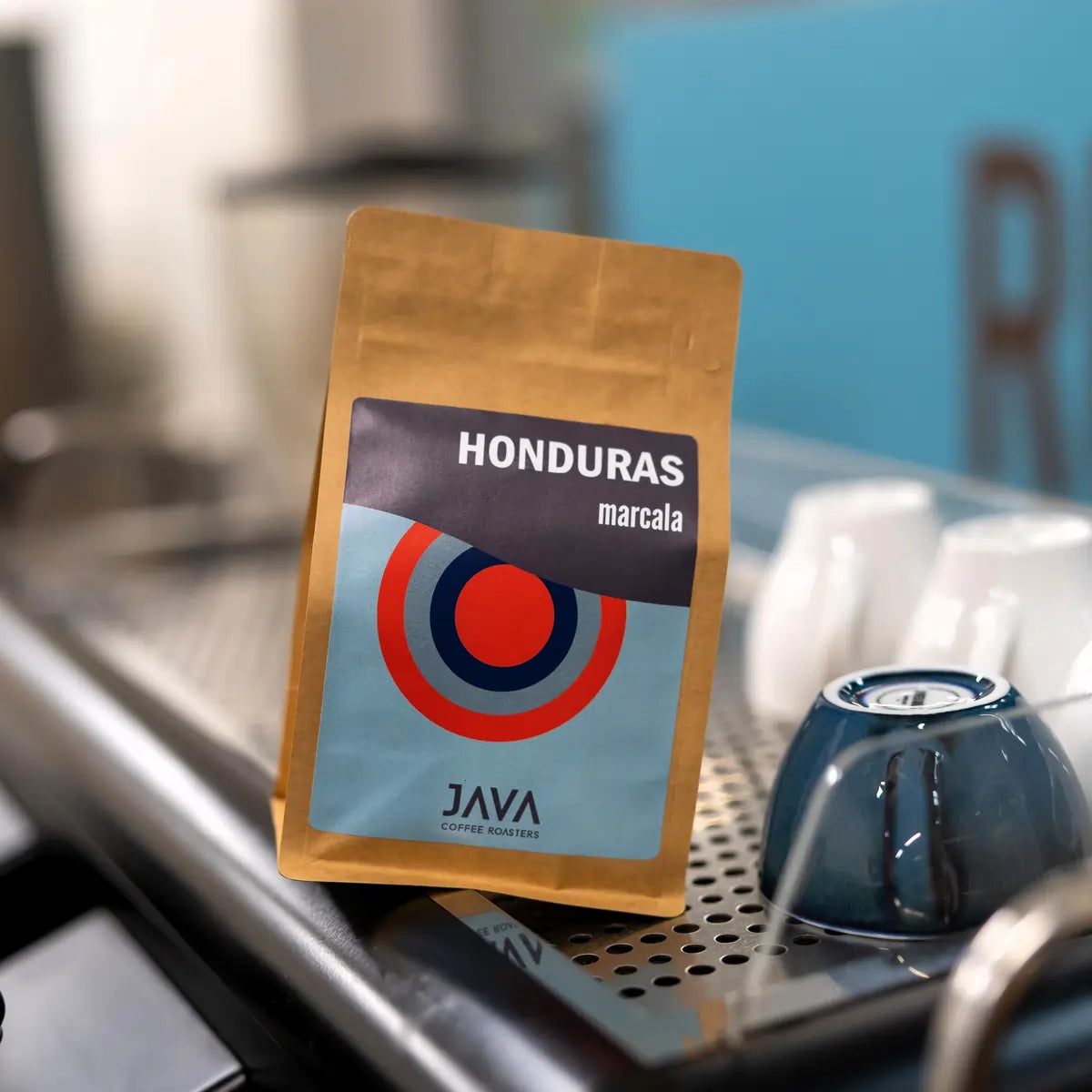Opakowanie kawy specialty Honduras Marcala od JAVA Coffee Roasters ustawione na ekspresie do kawy w kawiarni.