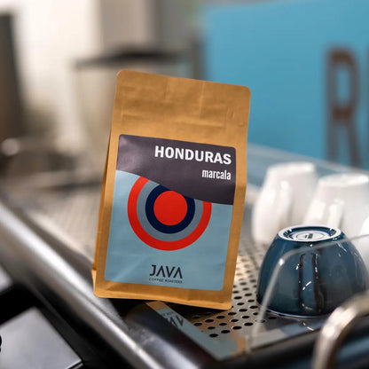 Opakowanie kawy specialty Honduras Marcala od JAVA Coffee Roasters ustawione na ekspresie do kawy w kawiarni.