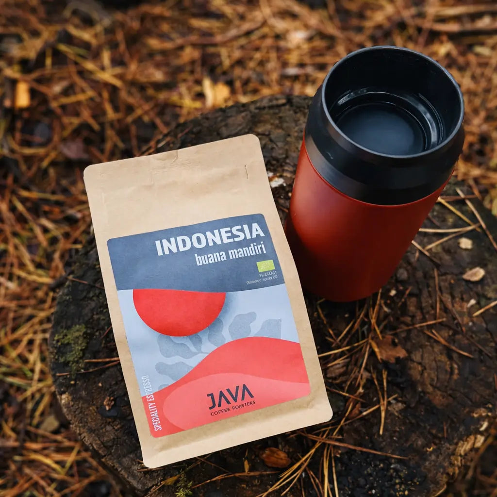 Kawa Specialty Indonesia Buana Mandiri JAVA Coffee – opakowanie kawy i kubek termiczny na pniu drzewa w leśnym plenerze