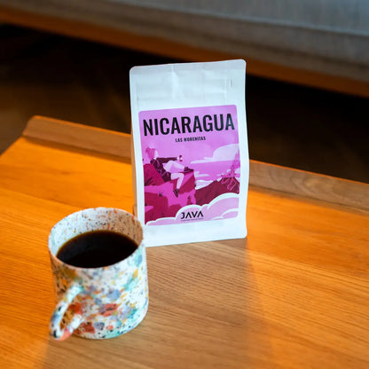 JAVA Coffee Nicaragua Las Morenitas kawa specialty – opakowanie kawy i filiżanka czarnej kawy na drewnianym stole