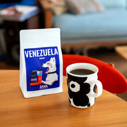 Kawa ziarnista Venezuela Merida 250g JAVA Coffee Roasters obok filiżanki czarnej kawy na stole