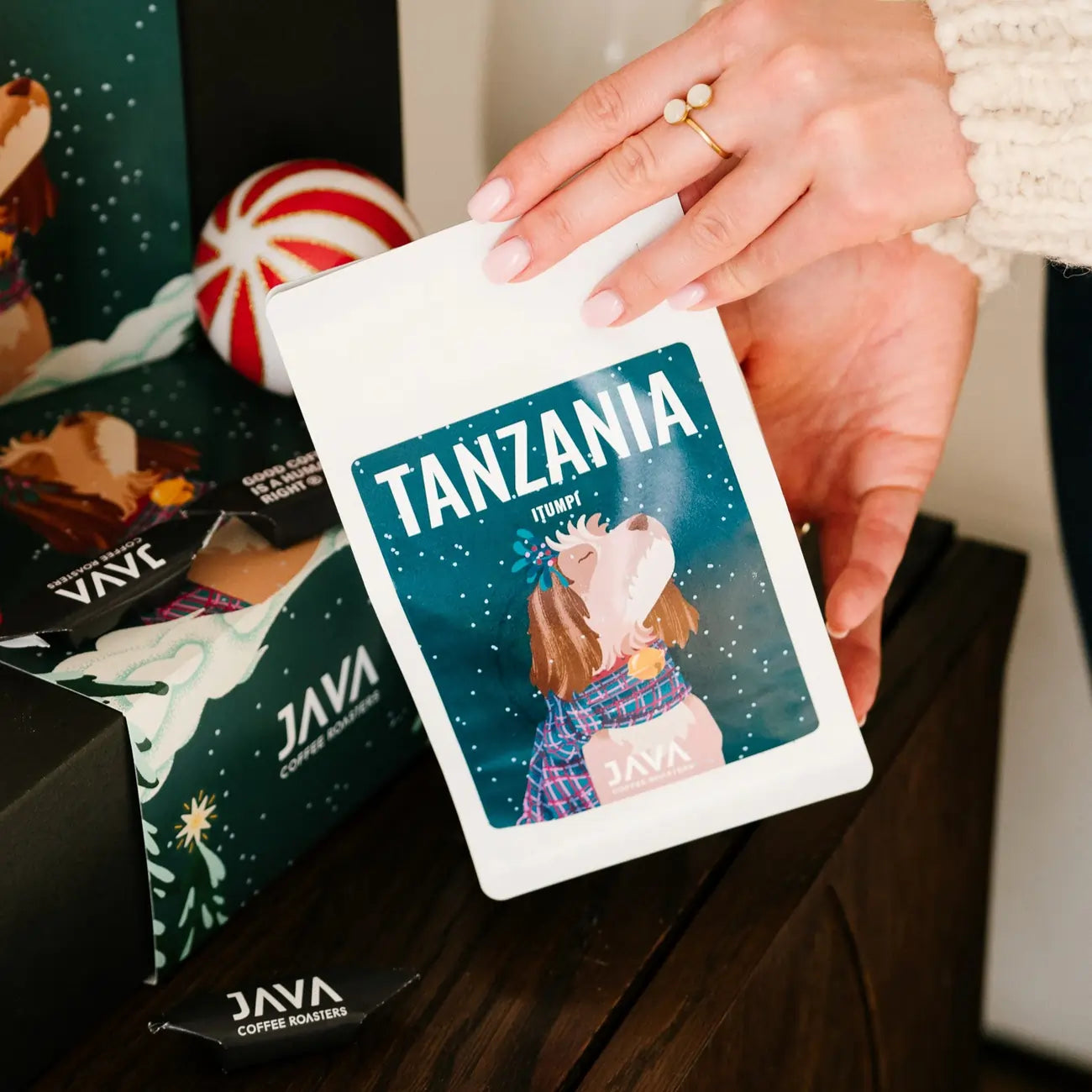 Opakowanie kawy JAVA Coffee Tanzania Itumpi trzymane przy świątecznym zestawie prezentowym z dekoracjami
