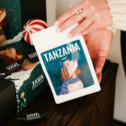 Opakowanie kawy JAVA Coffee Tanzania Itumpi trzymane przy świątecznym zestawie prezentowym z dekoracjami