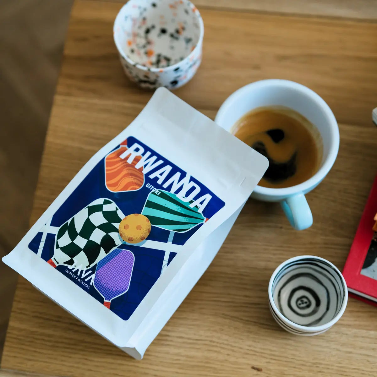 Kawa specialty Rwanda Gitoki JAVA Coffee Roasters i filiżanka espresso – ujęcie z góry na drewnianym stole