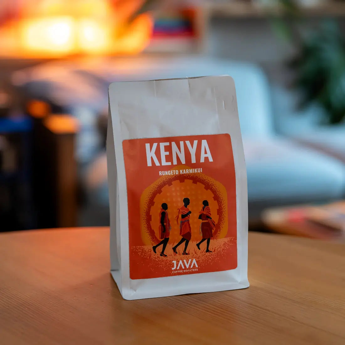 Kawa ziarnista Kenya Rungeto Karimikui JAVA Coffee Roasters w białym opakowaniu, zdjęcie lifestyle na drewnianym stole w domowym wnętrzu