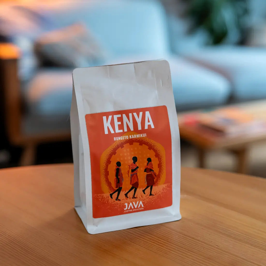 Kawa ziarnista Kenya Rungeto Karimikui JAVA Coffee Roasters w białym opakowaniu ustawiona na drewnianym stole, zdjęcie lifestyle