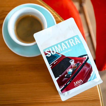 Kawa specialty Sumatra Asman Gayo Mill od JAVA Coffee Roasters – opakowanie kawy i filiżanka espresso, ujęcie z góry na drewnianym stoliku