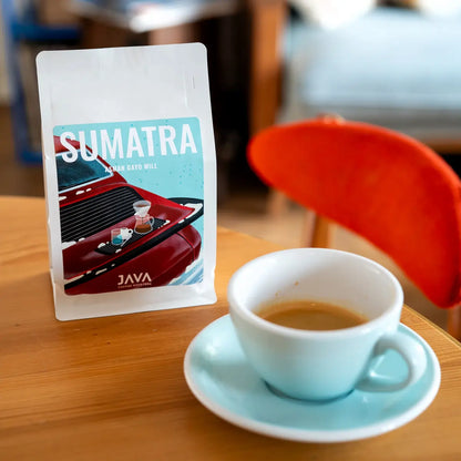 Kawa specialty Sumatra Asman Gayo Mill od JAVA Coffee Roasters – opakowanie kawy obok filiżanki espresso w ujęciu lifestyle w kawiarni