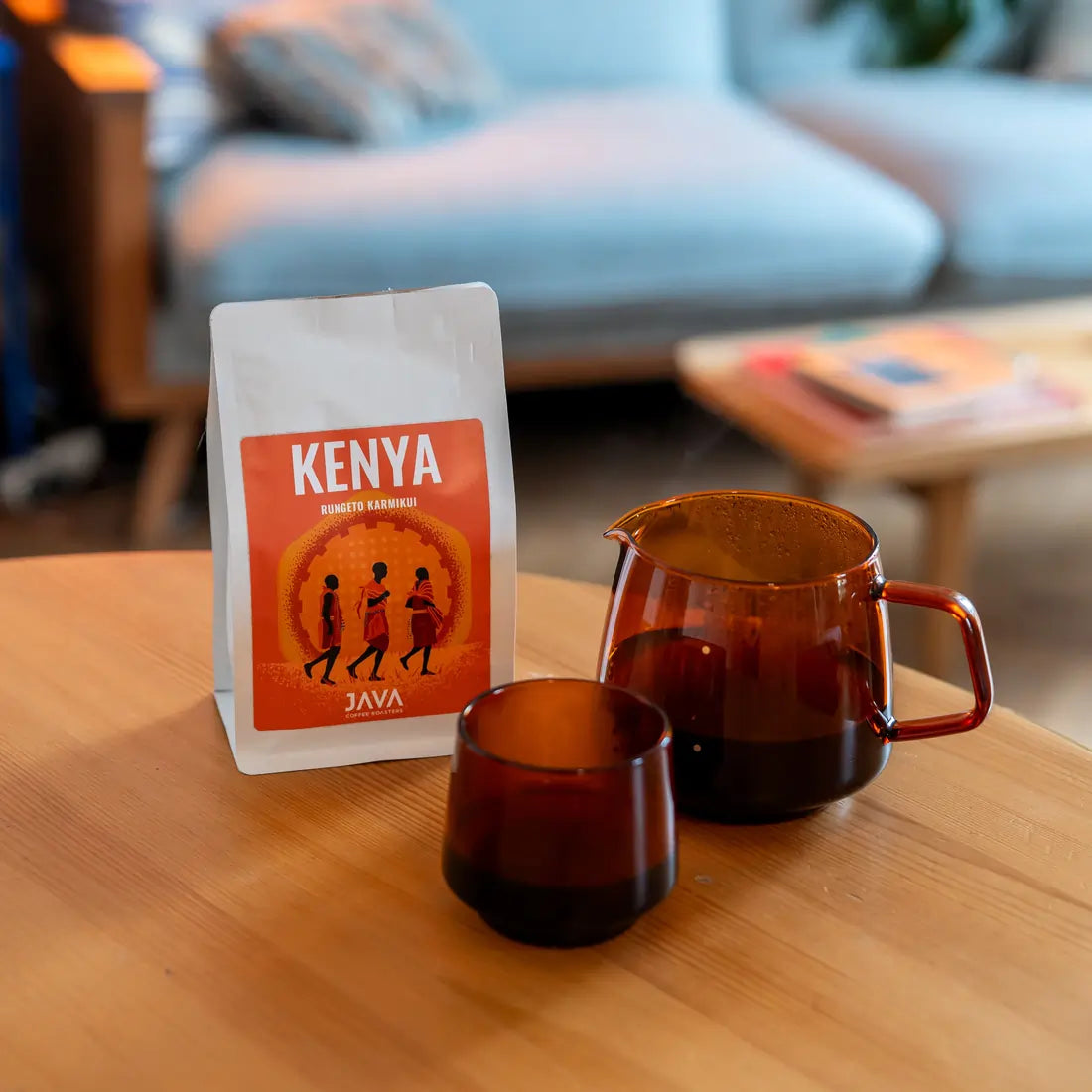 Kawa ziarnista Kenya Rungeto Karimikui JAVA Coffee Roasters w białym opakowaniu na stole z dzbankiem i filiżanką zaparzonej kawy