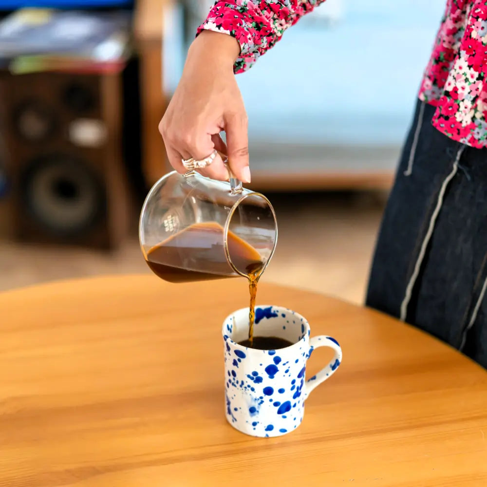 Wlewanie kawy przelewowej z szklanego dzbanka do ceramicznego kubka w stylu lifestyle