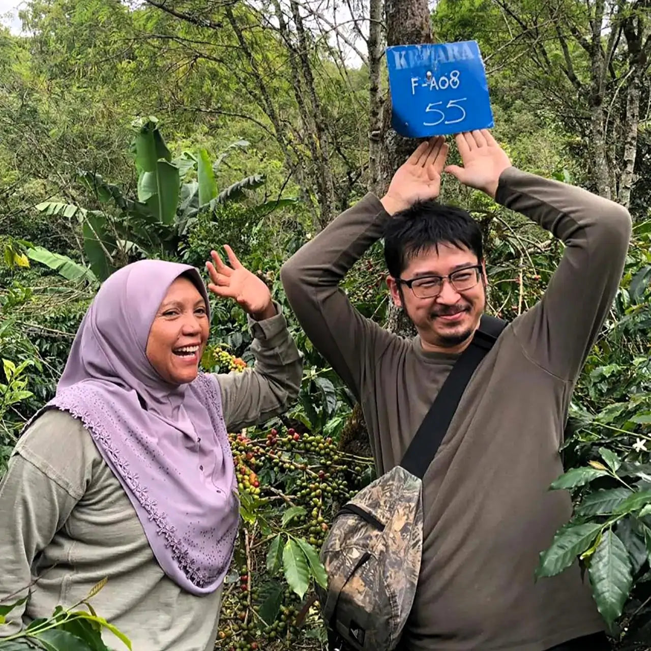 Kobieta i mężczyzna na plantacji kawy Ketiara w Indonezji – przy drzewie oznaczonym tabliczką „Farm 55”, wśród zielonych krzewów kawowca.