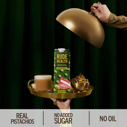Napój roślinny Rude Health Barista Pistachio 1L na złotej tacy z filiżanką kawy i pistacjami, elegancka kompozycja w stylu premium, bez dodatku cukru i oleju.