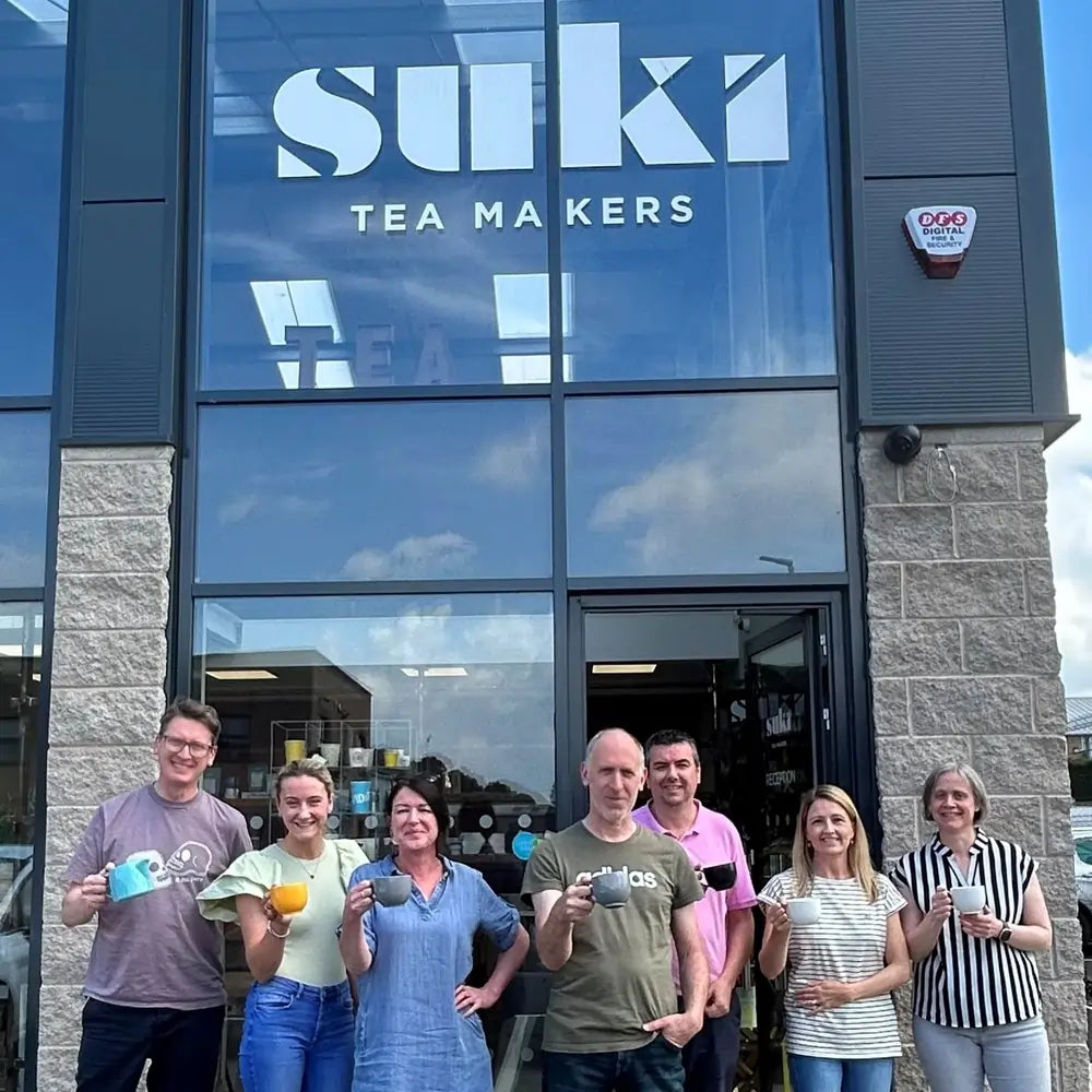 Zespół SUKI Tea Makers przed siedzibą marki, pracownicy trzymają filiżanki herbaty