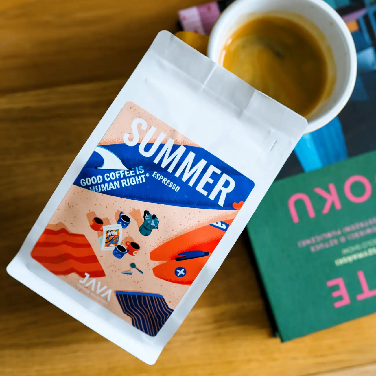 Opakowanie Summer Espresso JAVA Coffee Roasters obok filiżanki espresso i książki na drewnianym stoliku