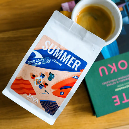 Opakowanie Summer Espresso JAVA Coffee Roasters obok filiżanki espresso i książki na drewnianym stoliku