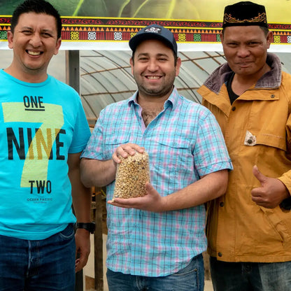 Producenci kawy z Indonezji oraz partner handlowy prezentują zielone ziarno kawy podczas wizyty na farmie – bezpośrednia współpraca u źródła